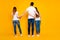 Full length back rear photo of two women and one man standing wearing white t-shirt denim jeans isolated over yellow