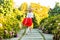 Full length back view of happy careless barefoot attractive young blonde woman in stylish red white dress walking with happiness