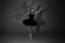 Full length black and white photo of beautiful young blonde ballet dancer in a black dress and pointes in complex pose