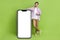 Full length body photo of young handsome businessman promoter marketing directing finger phone display isolated on green