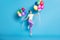 Full length body size photo of childish girl jumping high with piles of colorful balloons smiling isolated on vibrant