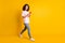 Full length body size photo of female millennial using app mobile phone walking isolated on vibrant yellow color