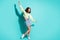 Full length body size photo of funky female dancer singing loudly keeping hand up isolated on vibrant teal color