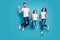 Full length body size photo of funny funky cheerful glad family jumping in front of camera while isolated with blue