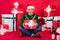 Full length body size photo happy guy sitting giving wrapped present box in headwear isolated bright red color