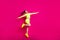 Full length body size photo of jumping sportswoman laughing cheerfully pointing at copyspace isolated on vibrant pink