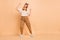 Full length body size photo of overjoyed dancing singing girl wearing headphones isolated on pastel beige color