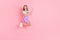 Full length body size photo of small girl jumping high showing fingers copyspace smiling isolated pastel pink color