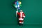Full length body size view of his he nice handsome cheerful bearded Santa holding in hands bunch helium balls giftbox