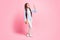 Full length body size view of slender lovely cheerful girl holding book waving hi hello isolated over pink pastel color