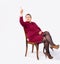 Full length of contented businesswoman, sitting on chair, pointing forefinger looking up, showing different business