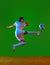 Full-length dynamic image of young girl, football athlete in motion, kicking ball against green studio background in