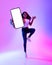 Full length of excited black woman jumping with cellphone, showing blank screen in neon light, mockup for website or app