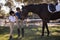 Full length of female jockey with sister feeding horse