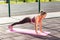 Full length, fit beautiful woman in tight pants practicing yoga on mat outdoor summer day, doing perfect plank asana