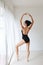 Full length flexible asian ballet dancer stretching on white wall studio