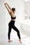 full length flexible asian ballet dancer stretching on white wall studio