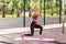 Full length, girl with athletic body in tight pants training on mat outdoor summer day, practicing split squats