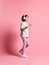 Full-length girl of music listens in white headphones, enjoying the pleasure of listening to music against a pink background