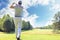 Full length of golf player playing golf on sunny day. Professional male golfer taking shot on golf course