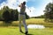 Full length of golf player playing golf on sunny day. Professional male golfer taking shot on golf course