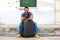 Full length handsome young african man sitting with suitcase and smart phone