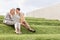 Full length of happy businesswomen looking at laptop while sitting on grass steps