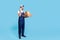 Full length happy friendly delivery man in uniform talking on cellphone, holding cardboard box. studio shot