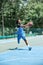 Full-length image of competitive young man in blue uniform playing basketball, throwing ball. Outdoor sportsground