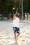 Full-length image of young bearded man in sunglasses playing beach tennis, hitting ball with racket. Summertime outdoor