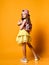 Full-length indoor portrait of a teenager girl in a yellow skirt. sneakers and a cap with a glamorous backpack.