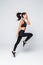 Full length of jumping fitness woman over gray background