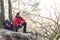 Full length of male hiker crouching on cliff in forest