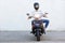 Full length of man in helmet riding a moped on road
