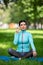 Full length outdoor portrait of a woman in lotus position inserts earphones to listening to the music for relaxation.