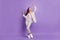 Full length photo of attractive funky young woman raise hands good mood dance isolated on purple color background