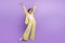 Full length photo of carefree impressed woman dressed yellow jacket rising hands arms empty space  purple color