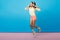 Full-length photo of carefree sporty caucasian girl dancing in sneakers on blue background. Glad brunette asian female