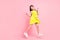 Full length photo of charming sweet school girl wear yellow dress eyewear jumping pointing empty space isolated pink