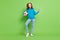 Full length photo of cheerful happy small girl hold hands football look empty space isolated on green color background