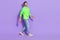 Full length photo of cool funny guy dressed neon sweatshirt walking empty space isolated violet color background