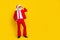 Full length photo of cool handsome man pensioner dressed red suit santa hat looking empty space isolated yellow color