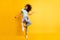 Full length photo of cute carefree dark skin curly girl dressed blue t-shirt dancing empty space isolated yellow color