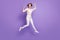 Full length photo of excited lucky young lady dressed white shirt rising fists jumping  purple color background