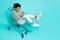 Full length photo of funky cool girl dressed hoodie sitting tray typing modern device empty space isolated teal color