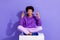 Full length photo of funky guy purple clothes sit on white platform look directing at sale empty space isolated on