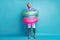 Full length photo of funky guy tourist get inside three colorful rubber lifebuoys going to swim pool sea ocean wear