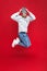 Full length photo of handsome man smiling and jumping isolated over red background