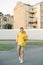 Full-length photo of a handsome young man in stylish summer clothes, wearing a yellow hoodie, shorts and sneakers, standing on the
