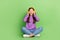 Full length photo of impressed girl wear jeans purple pullover arms touch headphones look empty space isolated on green